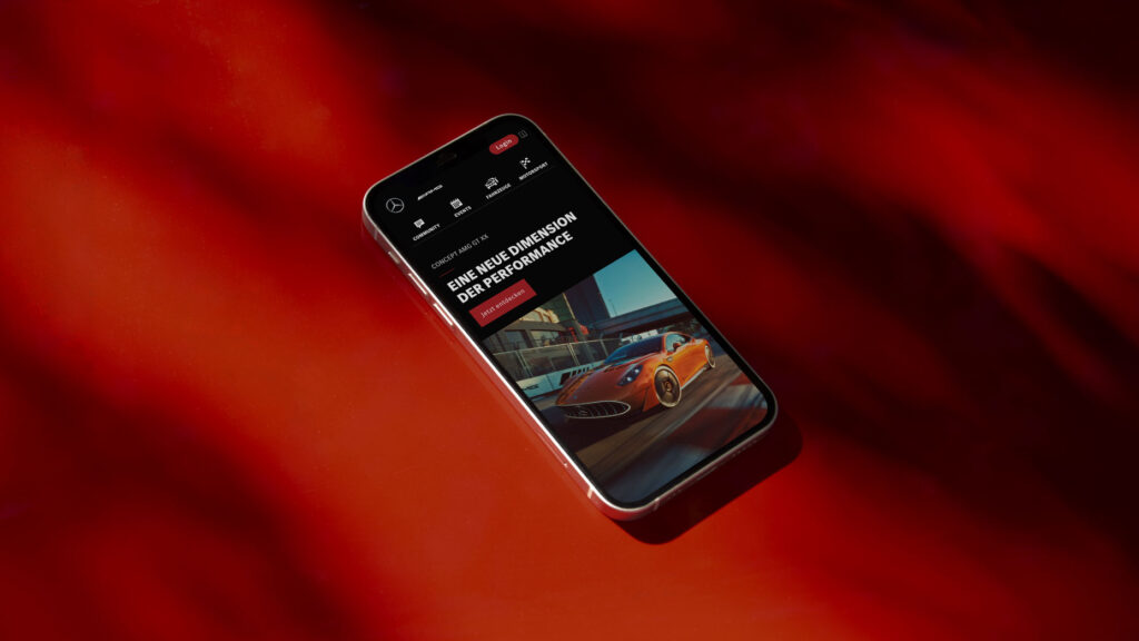 A mobile phone shows the AMG Homepage